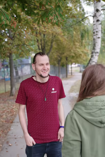 ich, lachend, mit zusammengebundenen Haaren, im Gespräch mit einer Person